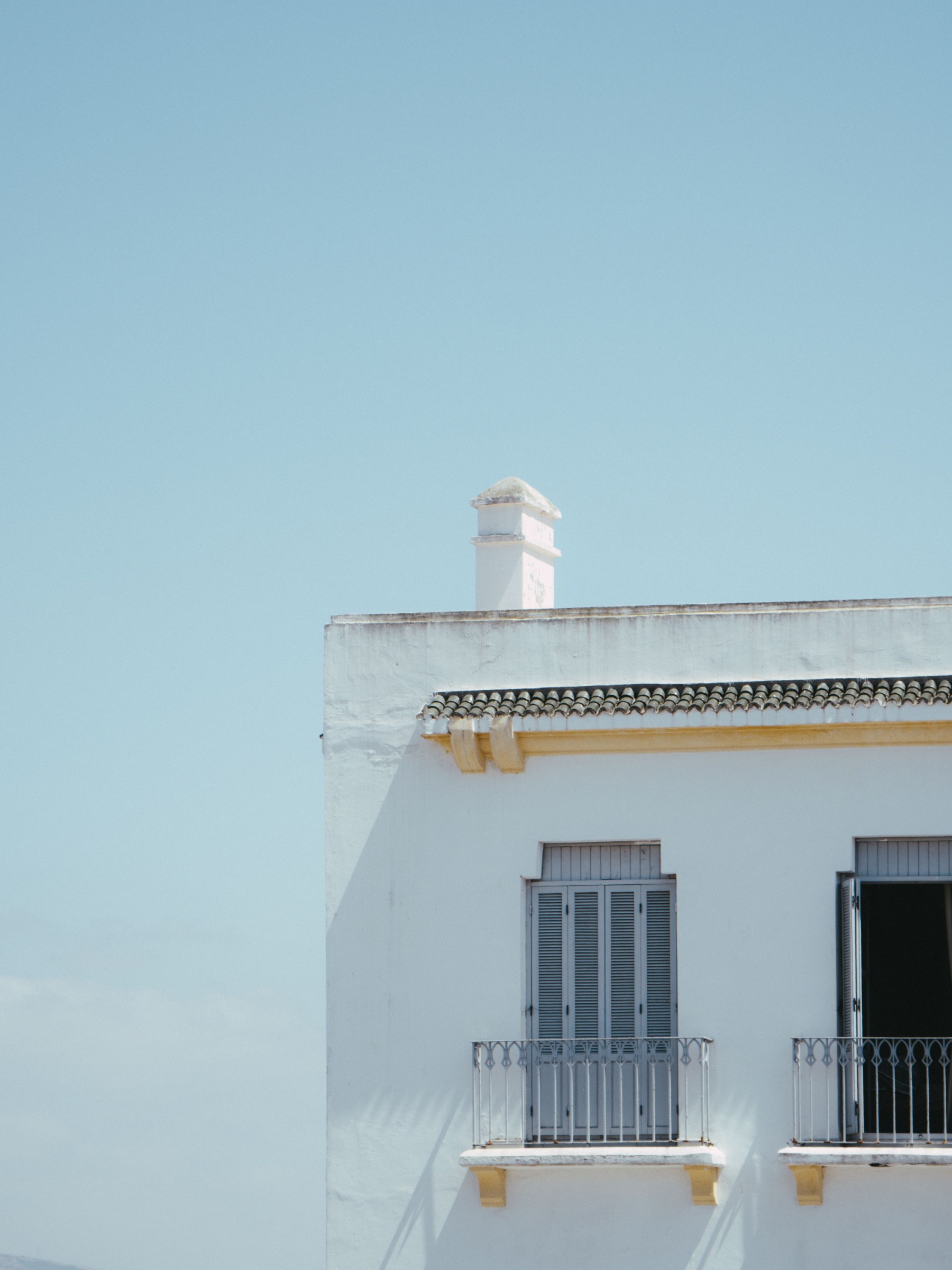 Whitewashed building with grey shutters and iron balconies